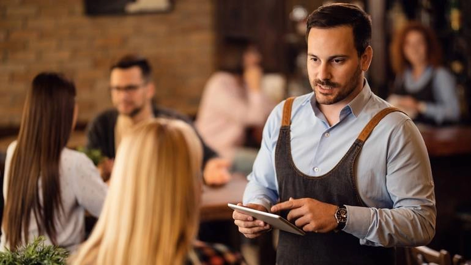 Kasse Südwest – ein professioneller Kellner in einem modernen Restaurant oder einer Kneipe, der ein digitales Tablet nutzt, um Kundenbestellungen effizient zu verwalten